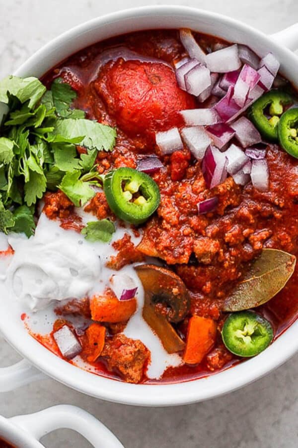 A bowl of turkey chili with jalapenos and sour cream.