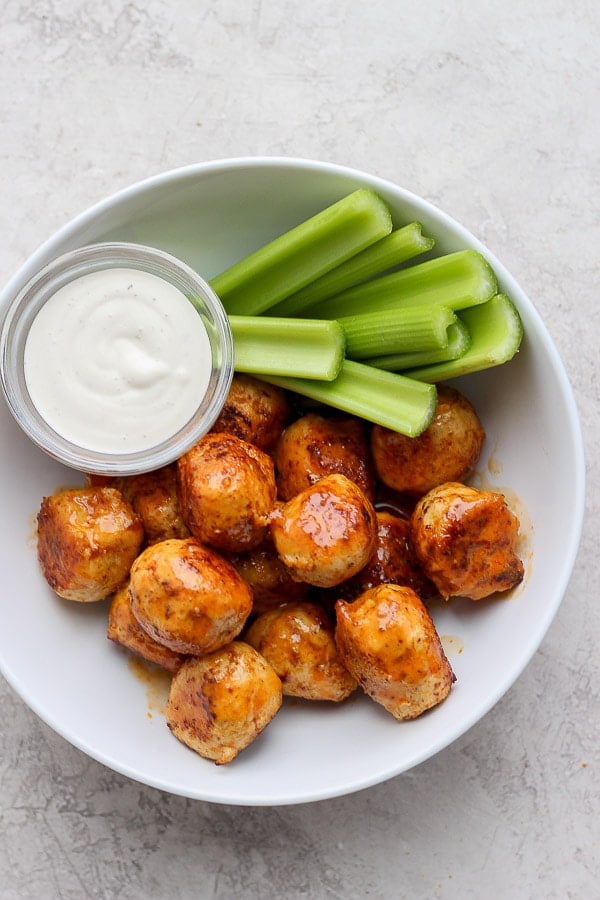 Buffalo chicken meatballs in a bowl with ranch and celery. 