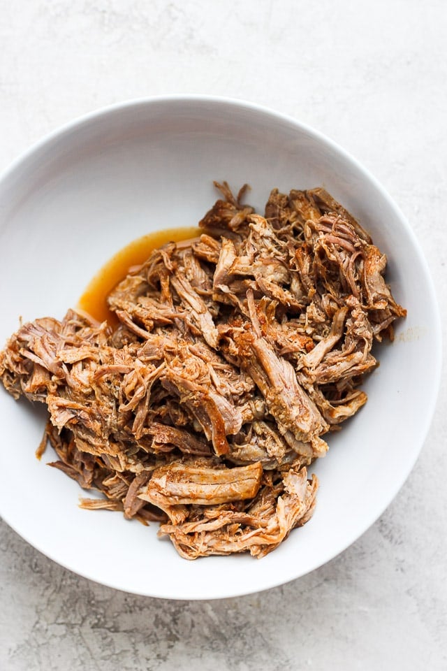 A white bowl with pulled pork inside. 