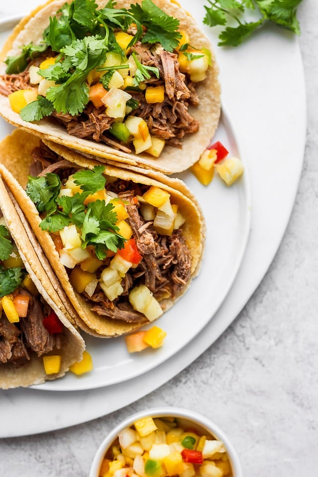 A plate of pulled pork tacos with mango salsa and fresh cilantro.