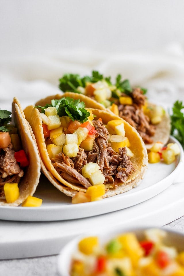 A plate of pulled pork tacos with mango salsa and fresh cilantro.