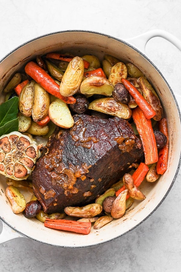 The pot roast in the dutch oven with roasted vegetables.