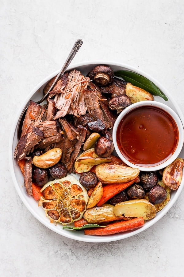 A full plate of meat and vegetables with the beef au jus on the side.