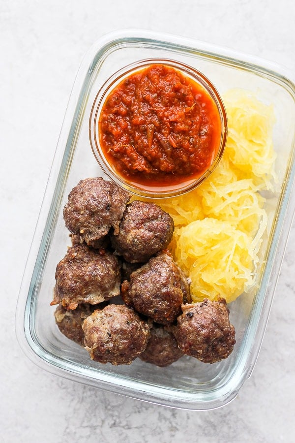 Baked meatballs in a meal prep container with spaghetti squash and marinara sauce.