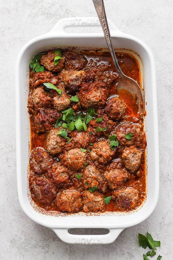 Meatballs and sauce in a white baking dish after baking.