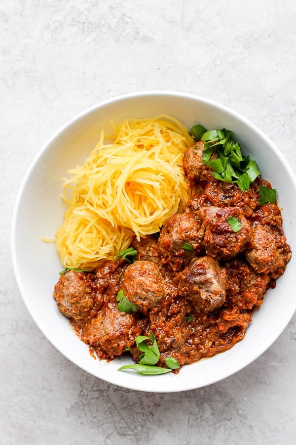 Baked Italian meatballs in a white bowl with spaghetti squash.