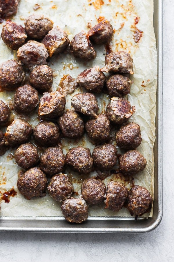 Oven baked meatballs on a baking sheet after cooking.