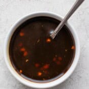 A spoon sticking out of a small bowl of paleo teriyaki sauce.