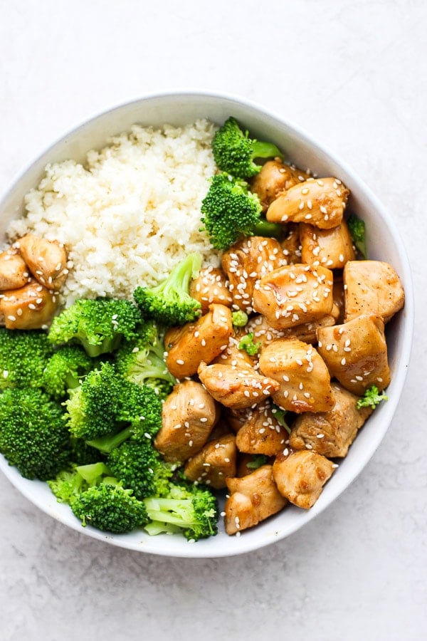 Healthy orange chicken in a bowl with broccoli and cauliflower rice. 