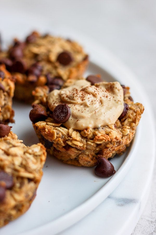 Baked oatmeal cup on a plate topped with almond butter and cinnamon.