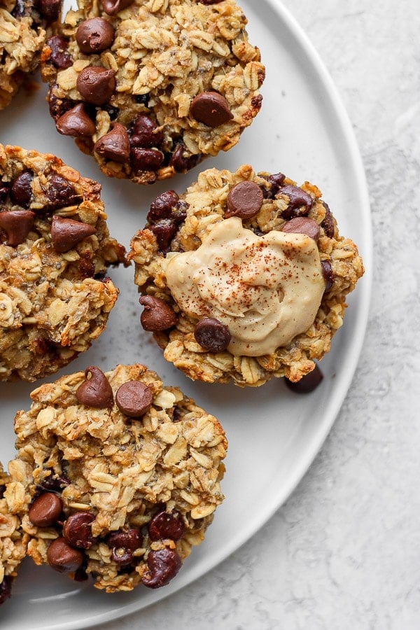 Top view of baked oatmeal cups on a plate topped with almond butter and cinnamon. 