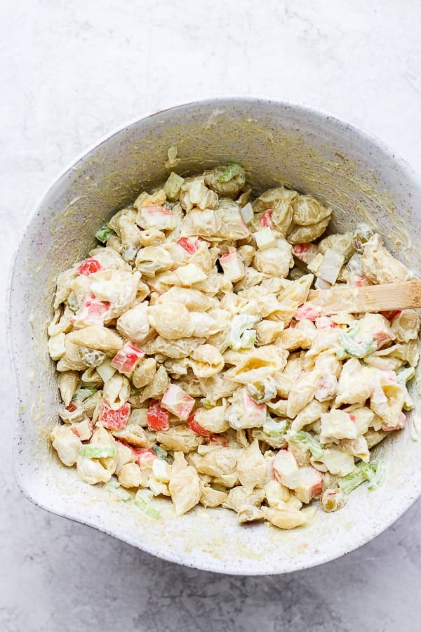 Fully mixed crab pasta salad in a mixing bowl.