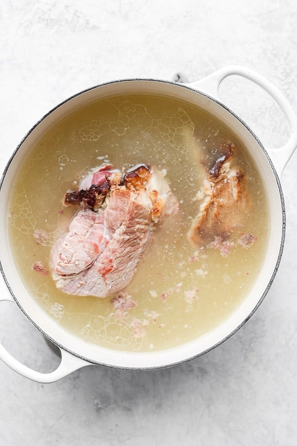 A ham bone simmering in water in a large dutch oven.