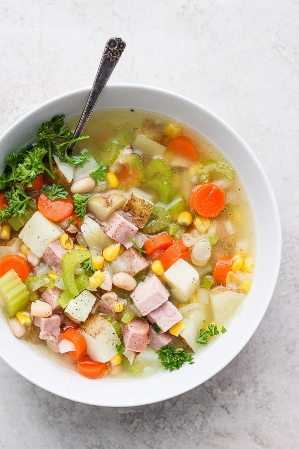 Leftover ham bone soup in a white bowl with a spoon.