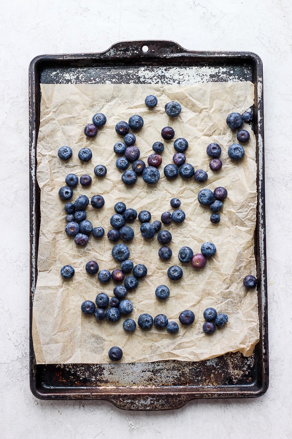 A parchment-lined baking sheet with clean blueberries on it.