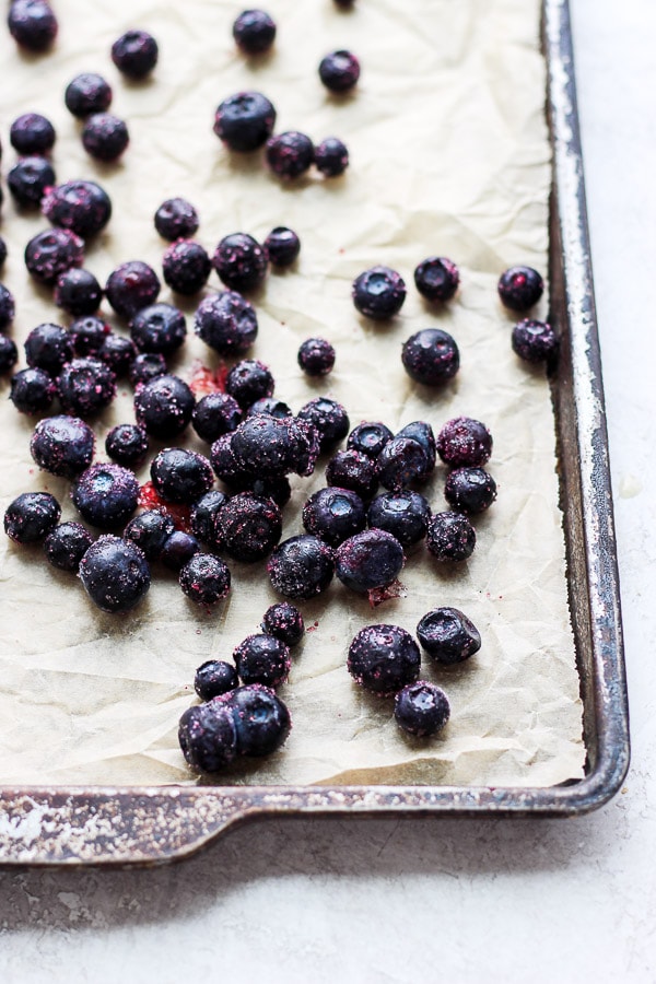 Frozen blueberries on a parchment-lined baking sheet.