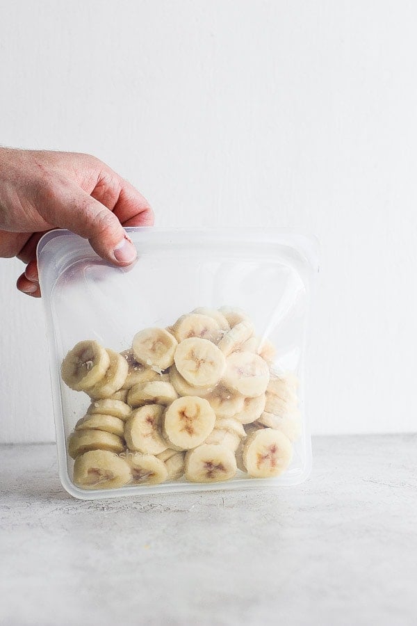 A hand holding a bag of frozen banana slices.