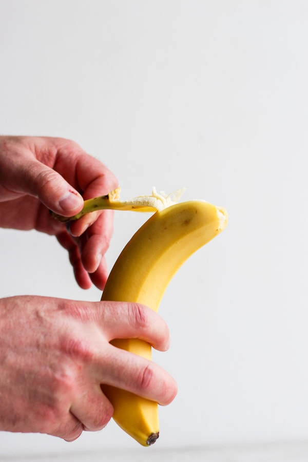 Two hands peeling a banana.