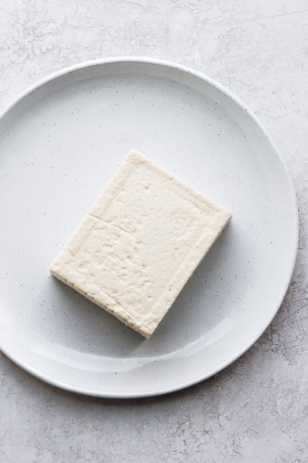 A block of tofu on a white plate.