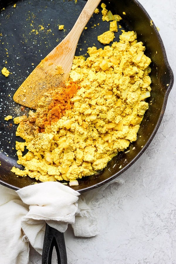 Tofu scramble in a skillet with a wooden spoon.