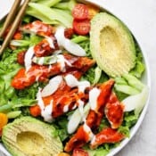 A fully assembled crispy buffalo chicken salad in a large white bowl.