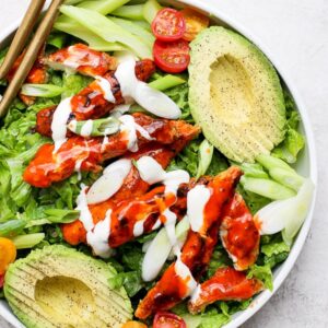 A fully assembled crispy buffalo chicken salad in a large white bowl.