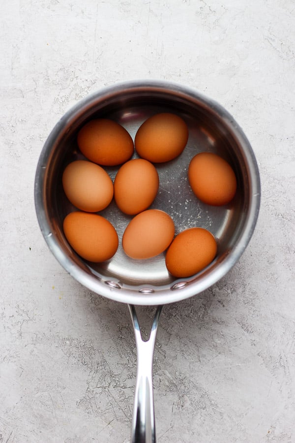 A saucepan with boiled eggs inside with water.