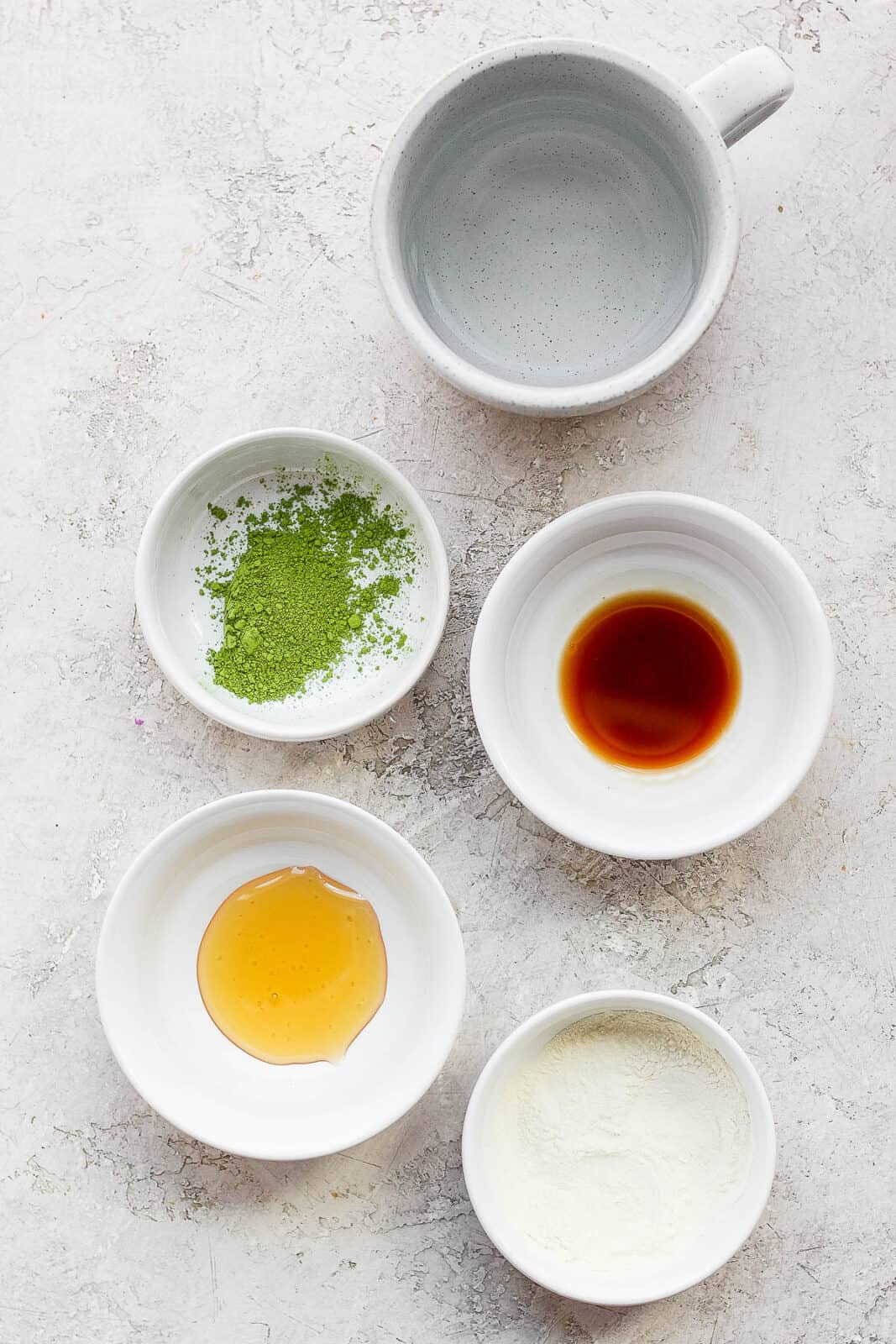 Small bowls filled with ingredients for a matcha latte.