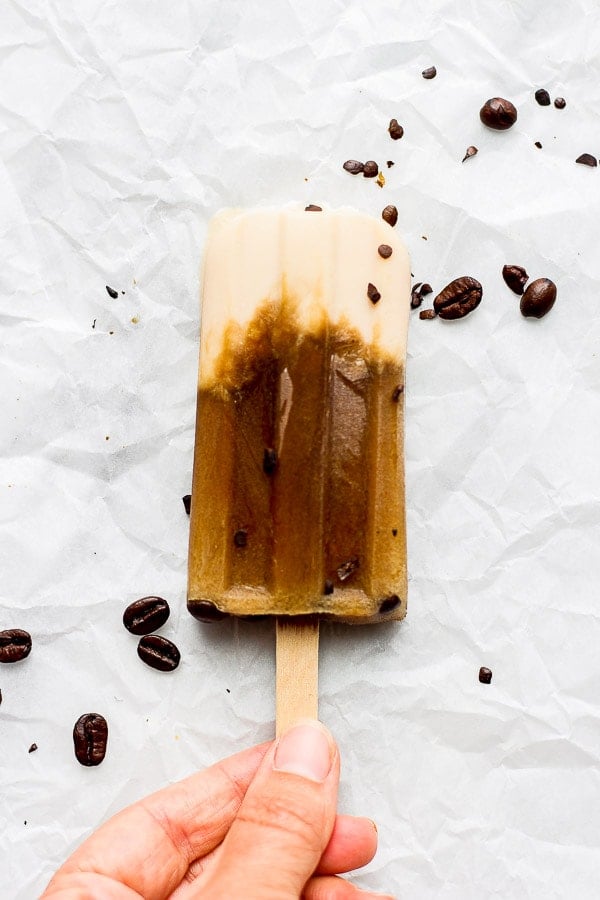 A person holding a coffee popsicle. 