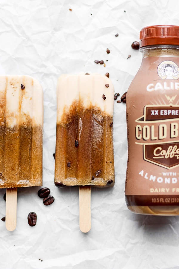 Two coffee popsicles next to a Califia Farms cold brew bottle.