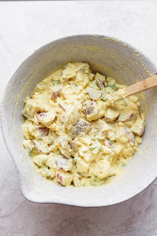 Deviled Egg Potato Salad all mixed in one bowl with a wooden spoon.