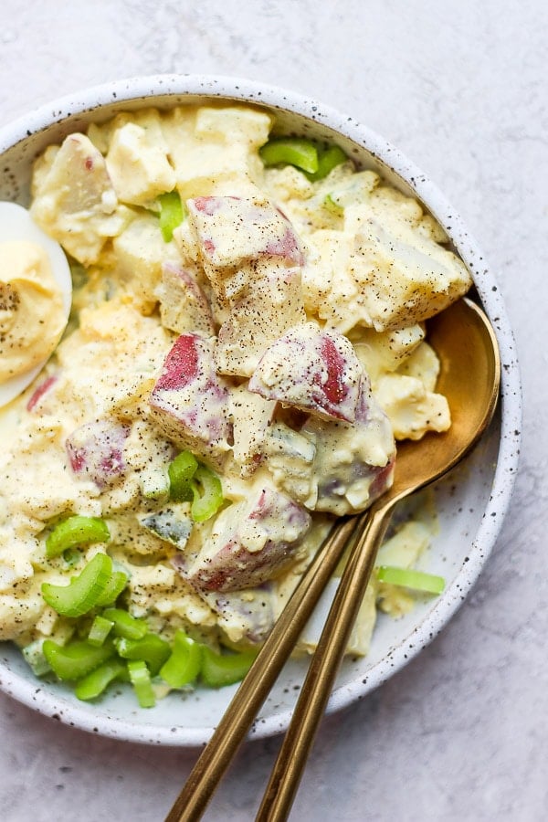 Close up shot of the potato salad with some pepper on top.