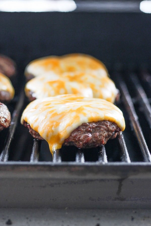 A cheeseburger on the grill. 