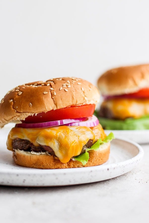 A cheeseburger on a bun sitting on a plate. 