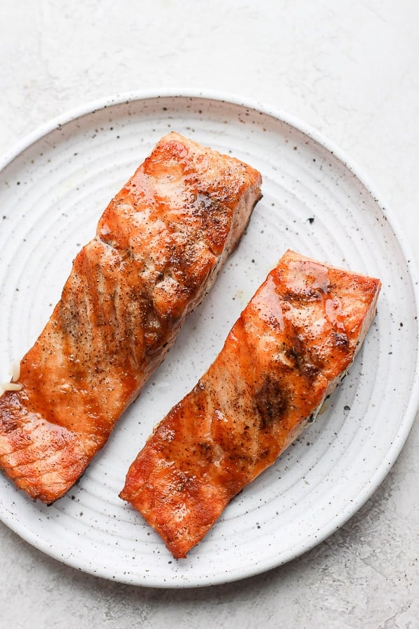 Two pieces of grilled salmon on a plate. 