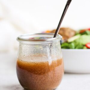 Creamy balsamic dressing in a jar with a spoon.