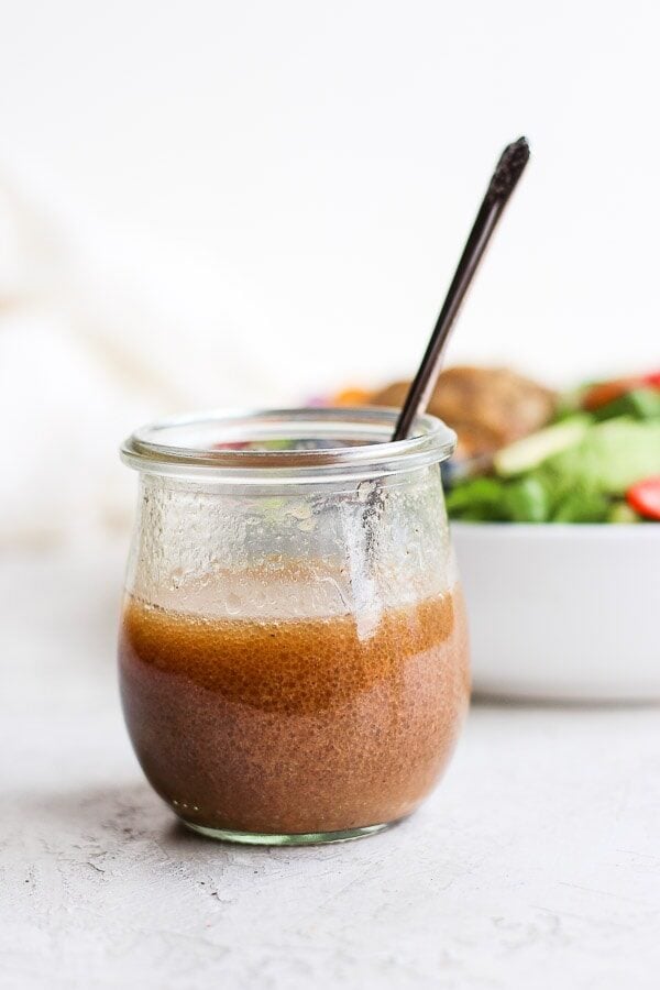 Creamy balsamic dressing in a jar with a spoon.