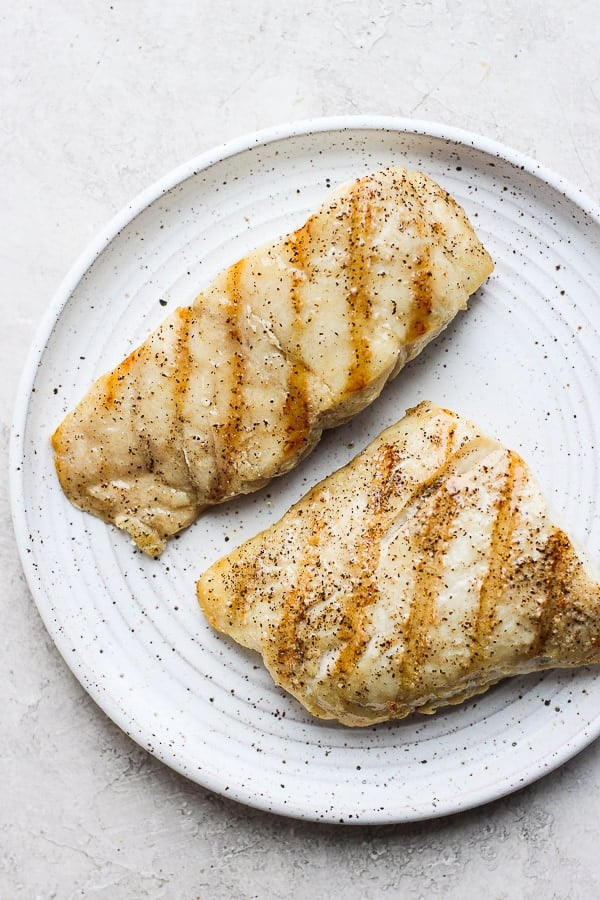 Two pieces of grilled red snapper on a plate. 