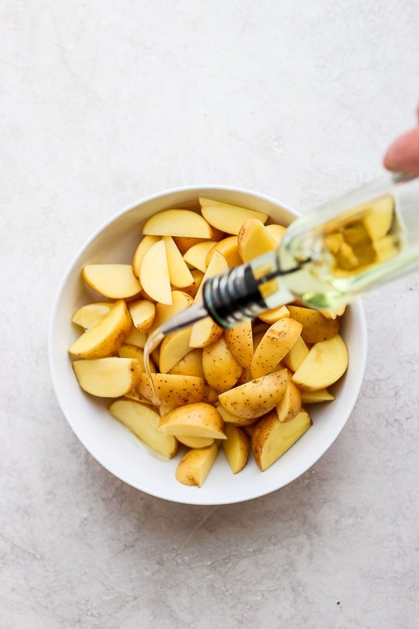 Olive oil being drizzled on the potatoes.