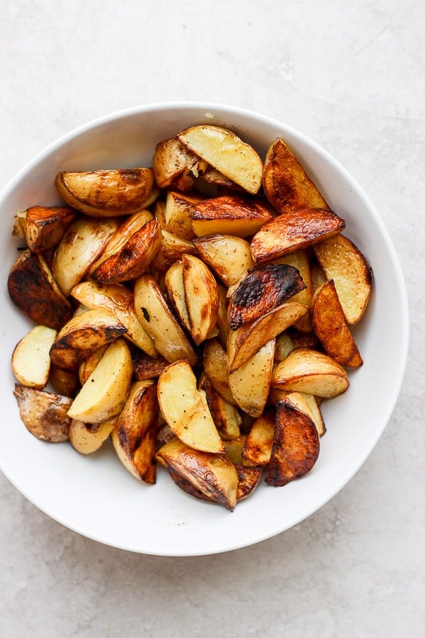 Grilled potato wedges in a white bowl.