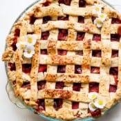 A glass pie plate with a fully cooked strawberry rhubarb pie.