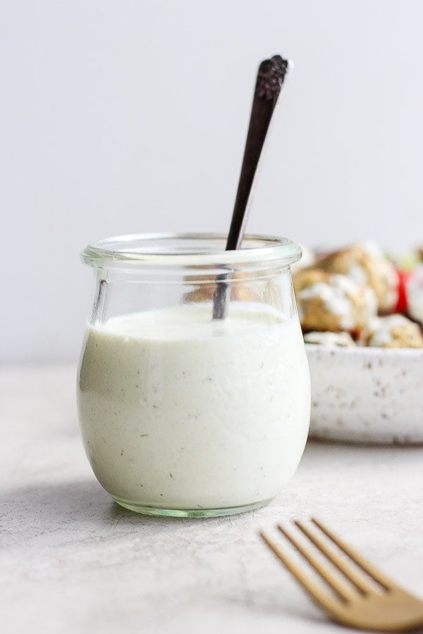 Jar of dairy free Tzatziki Sauce with a spoon sticking out of it.