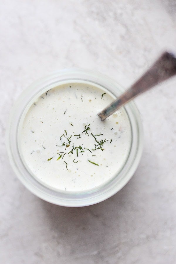 Top shot of some dairy free Tzatziki Sauce in a jar with a spoon sticking out.