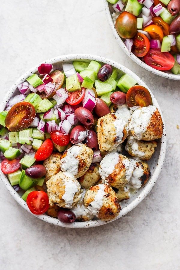 Greek chicken meatballs in a bowl with a greek salad. 