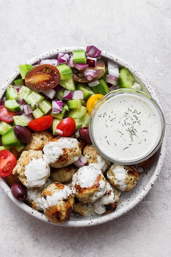 Greek chicken meatballs in a bowl with homemade tzatziki sauce. 