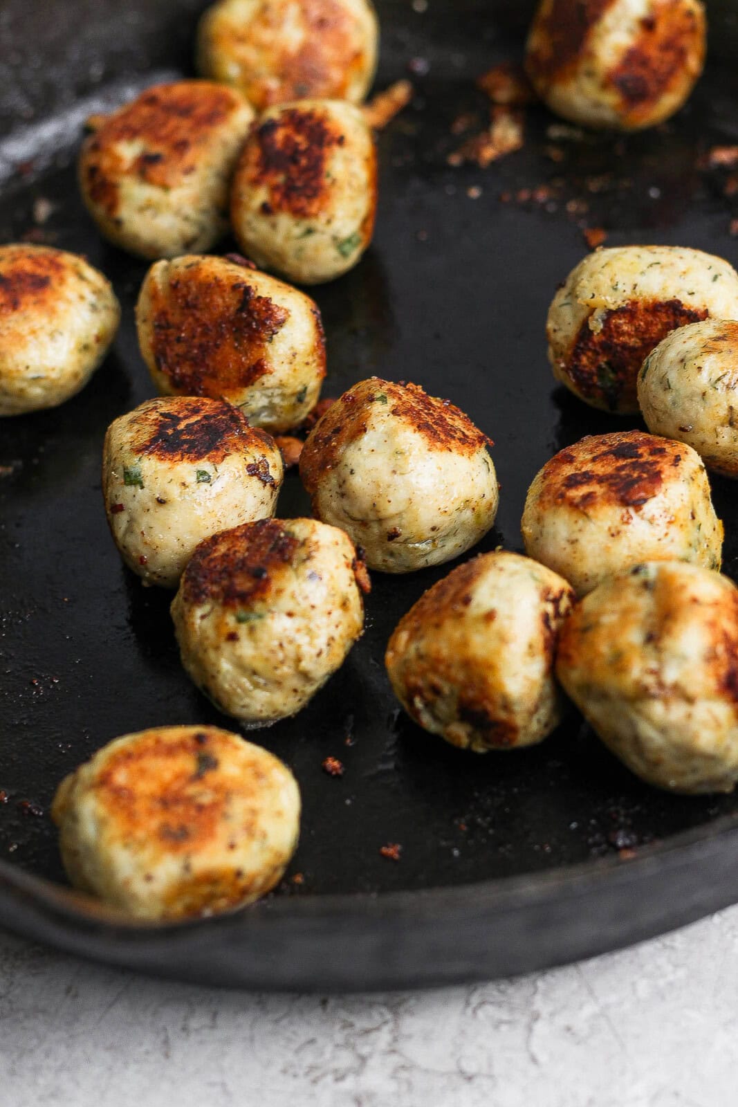 Greek chicken meatballs cooked in a cast iron skillet. 