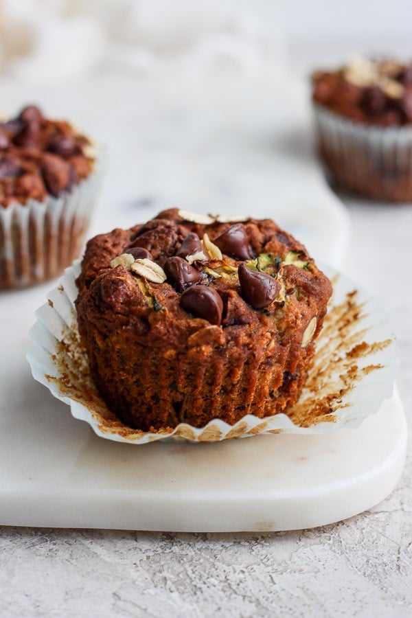 One zucchini muffin on the counter with the paper pulled down.