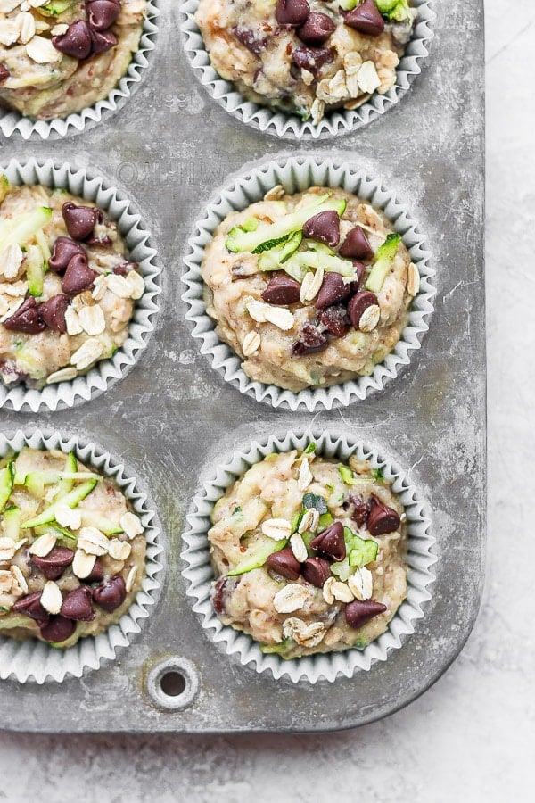 The zucchini muffin batter in paper liners in the muffin tin.