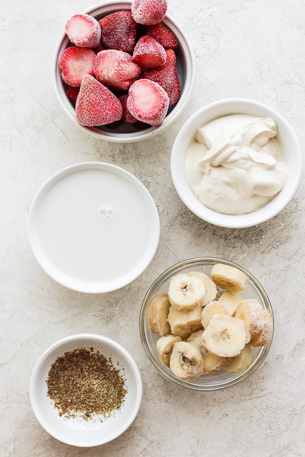 Ingredients for a strawberry smoothie in small bowls.