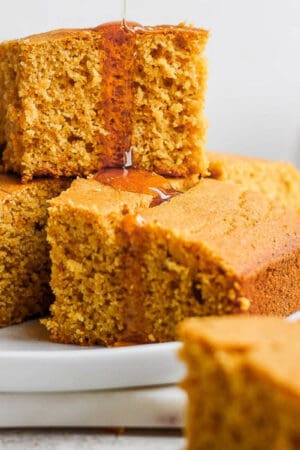 A stack of gluten free cornbread slices with honey dripping down.